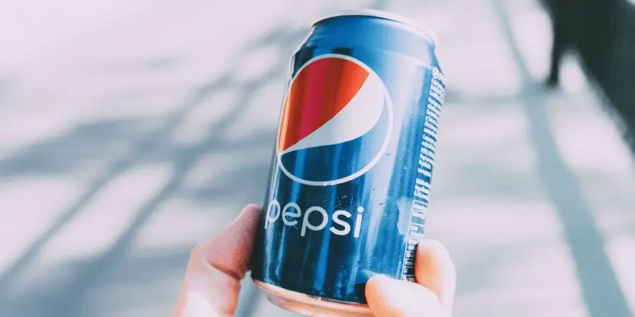 A Pepsi soda can held in hand, approximately 5 inches tall.