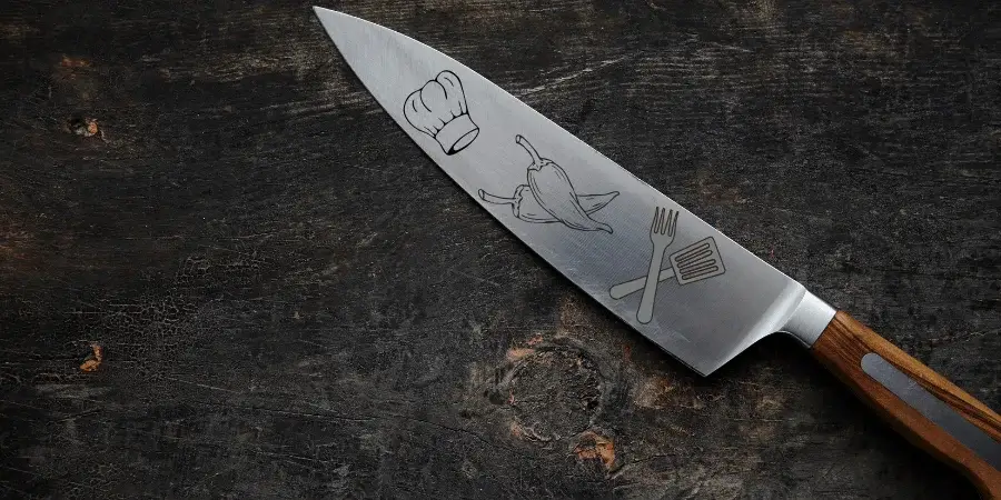 Sharp kitchen knife with engraved designs, approximately 7 inches in length.