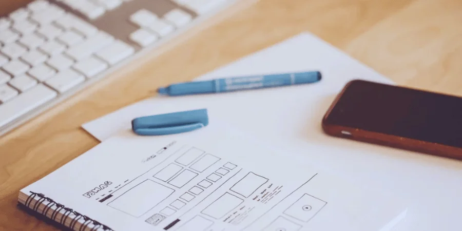 A desk with a notepad, pen, phone, and a keyboard.