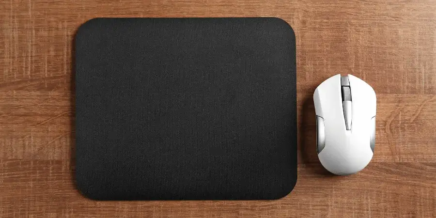 A black mouse pad next to a white computer mouse.