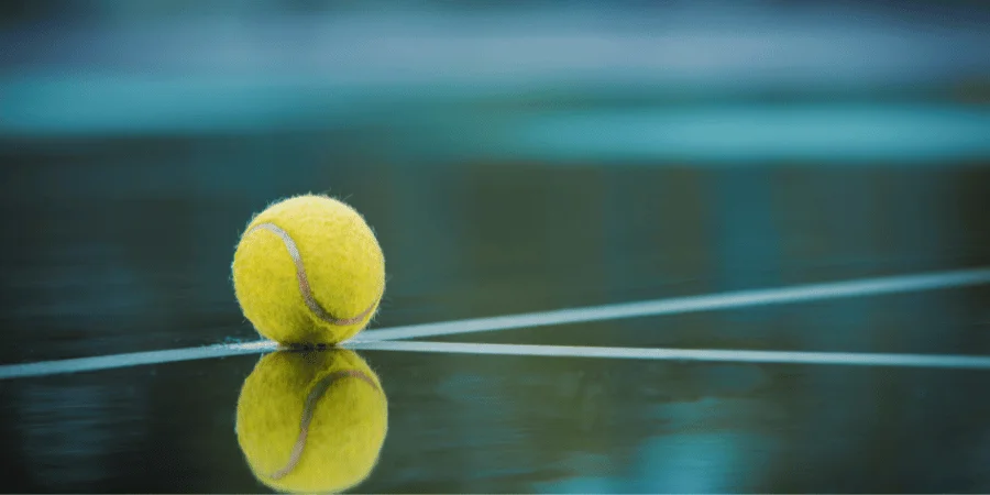 A yellow tennis ball resting on a court, close to 3 inches in diameter.