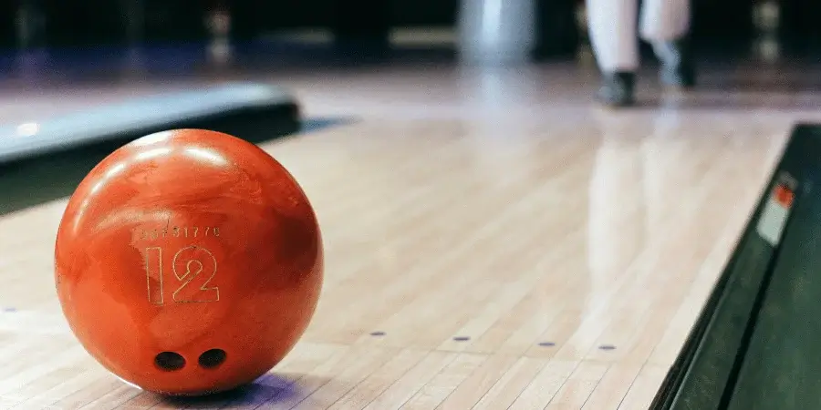 A bright orange bowling ball resting on a bowling lane, ready for the next throw.