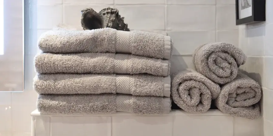 Neatly stacked and rolled towels in a bathroom setting. 