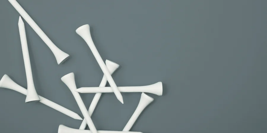 A collection of white golf tees, each measuring about 2 inches.