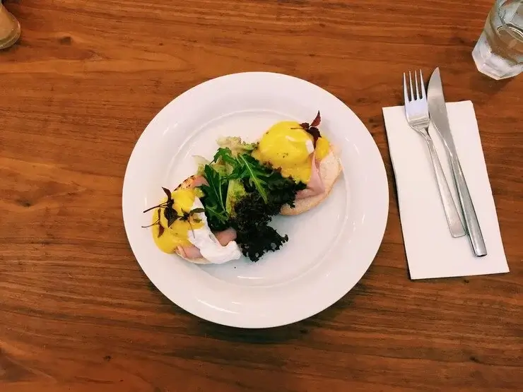 A plate of eggs benedict with vegetables and hollandaise sauce.