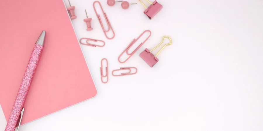 Pink stationery including paper clips and a pen, with one paper clip measuring 1 inch.