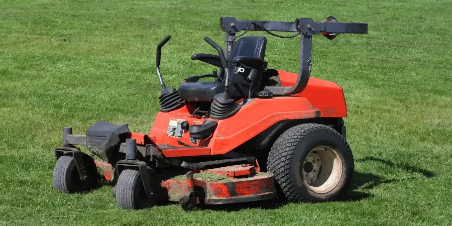 A small, red lawn mower ideal for maintaining grass and landscaping.
