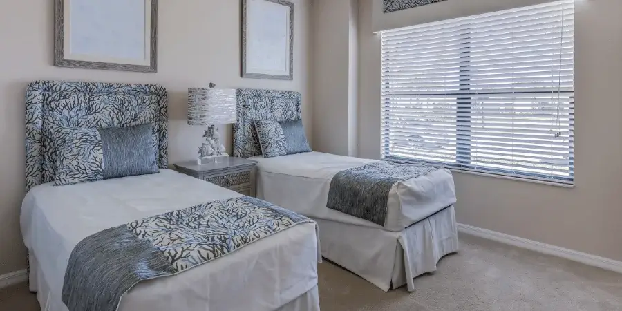 Two twin-size beds with blue bedding in a cozy bedroom.
