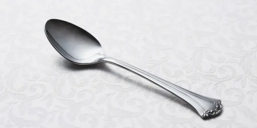 A silver spoon placed on a textured white tablecloth.