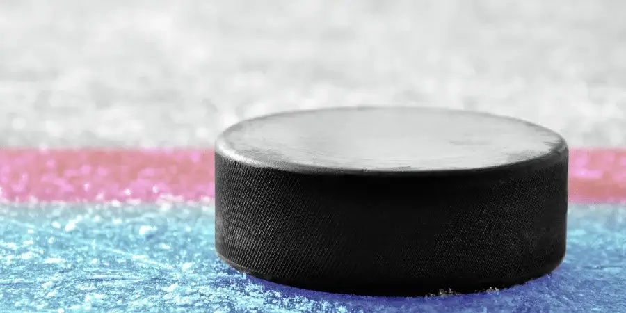A black ice hockey puck on a colorful ice rink surface.