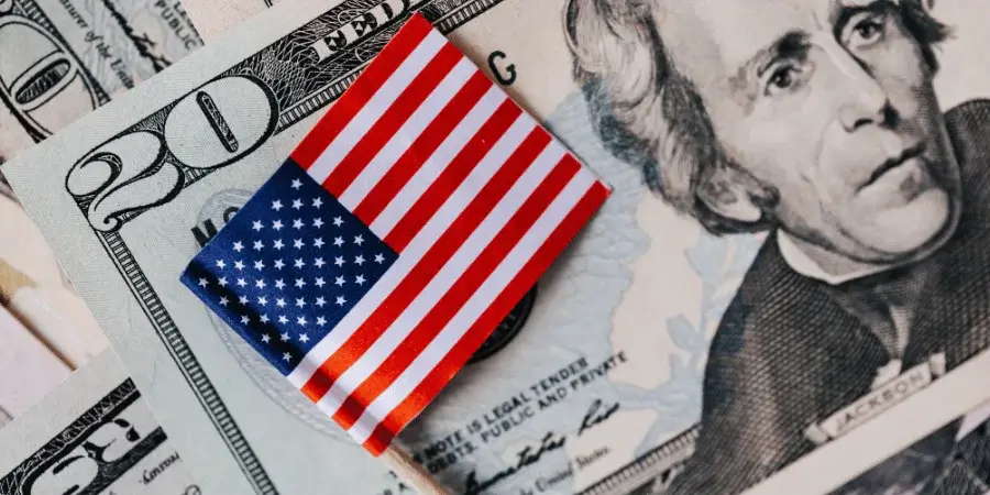A US dollar bill with an American flag placed next to it for size reference.