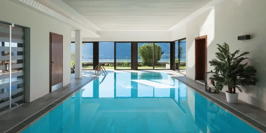 Modern indoor swimming pool with large windows offering scenic views.