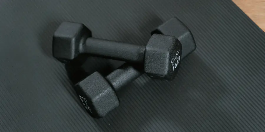 A pair of 10 lb dumbbells resting on a textured black exercise mat, ready for a workout session.
