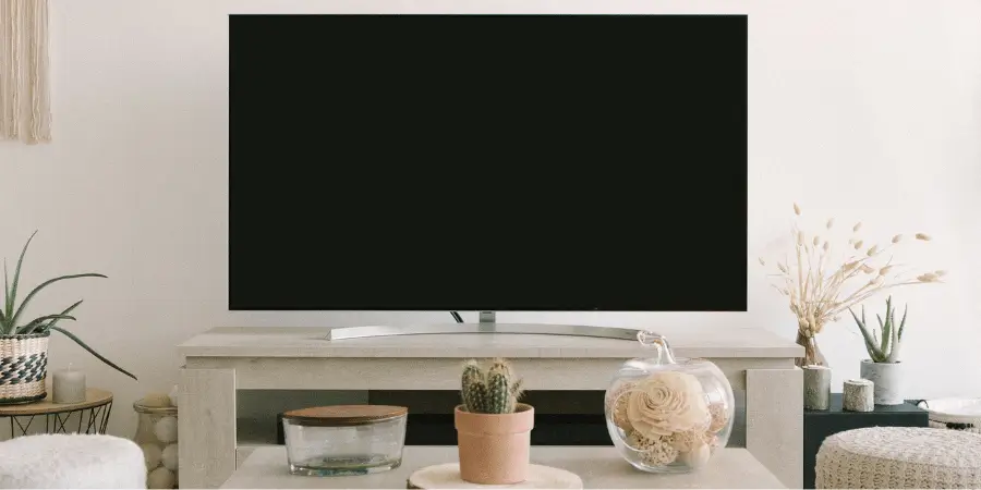 A large 75-inch flat-screen television mounted on a modern living room wall with decor. About 100 Kg