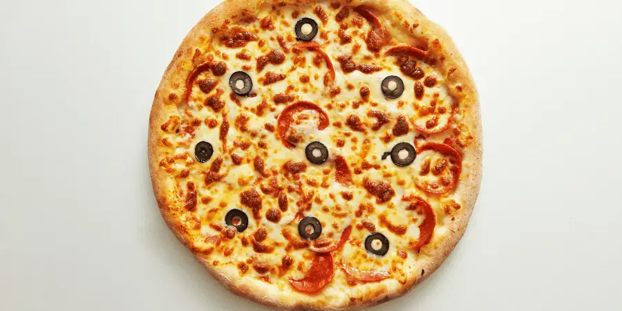 A large pizza with melted cheese, pepperoni, and black olives, ready to be served.