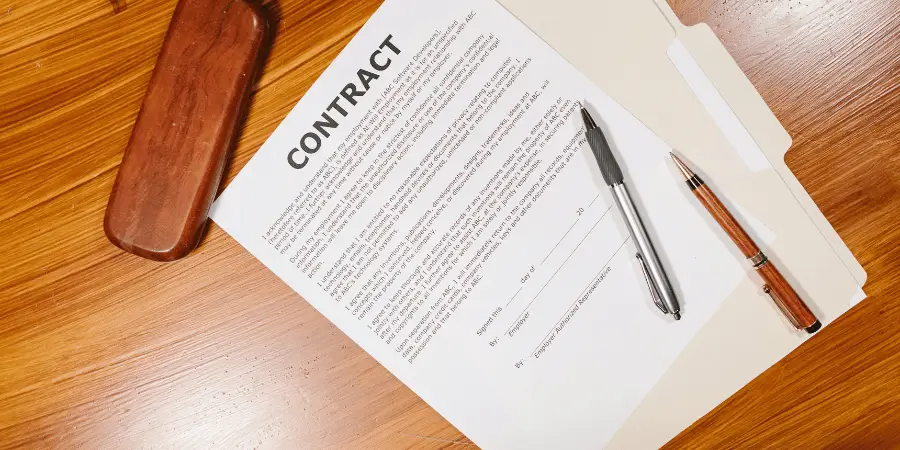 A signed contract document with a silver pen and wooden folder placed on a wooden desk, ready for business finalization.