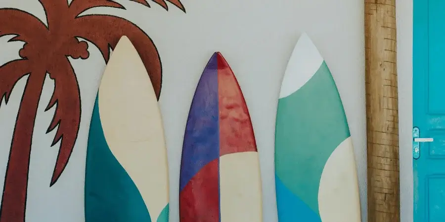 Three surfboards leaning against a wall, representing four boards that weigh 30kg together.