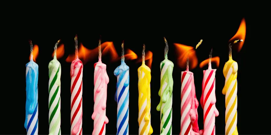 Ten colorful birthday candles with flames, ready to be used for a birthday celebration.