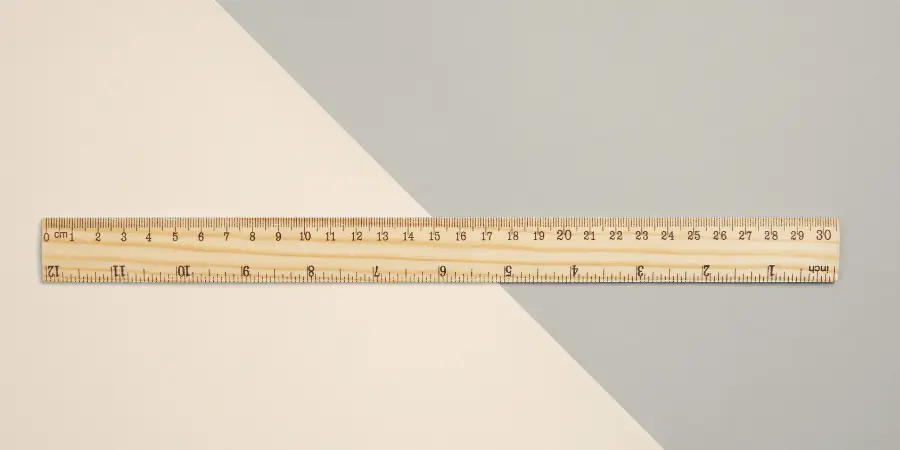 A wooden ruler with both metric and imperial measurements, placed on a neutral background.