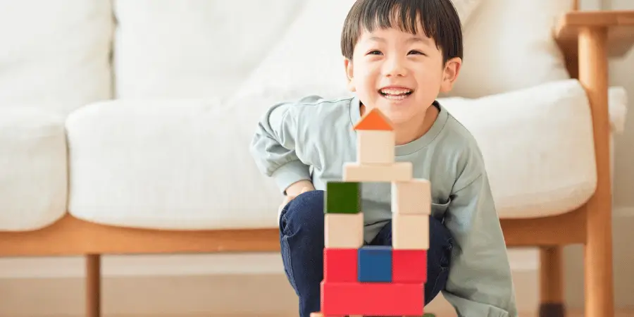 Happy child playing with building blocks, smiling as they create a tower.