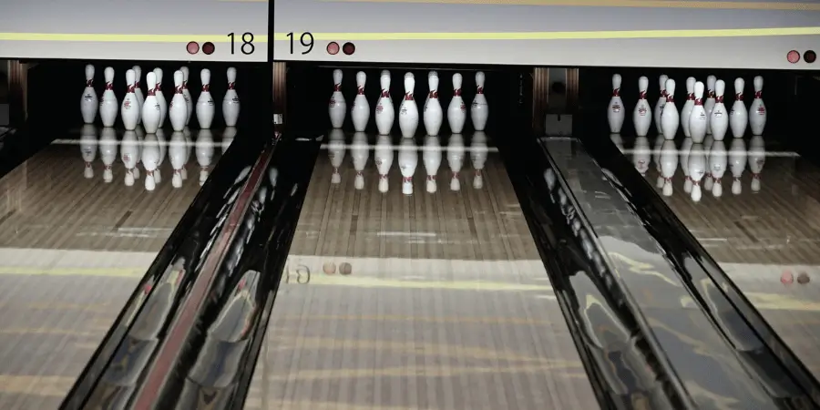 Bowling lane with ten white pins neatly arranged, ready for the next roll, inside a modern bowling alley.