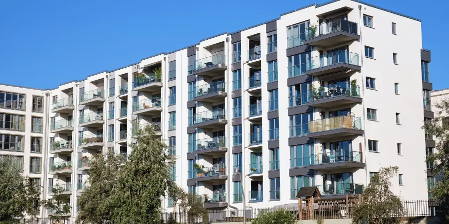 Modern apartment building with glass balconies and a clear blue sky in the background.