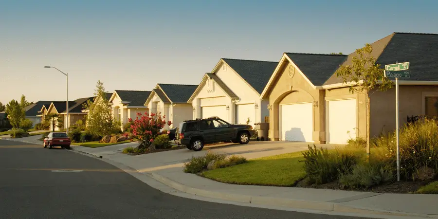 Suburban street with well-kept houses and neatly parked cars, showcasing a peaceful neighborhood.