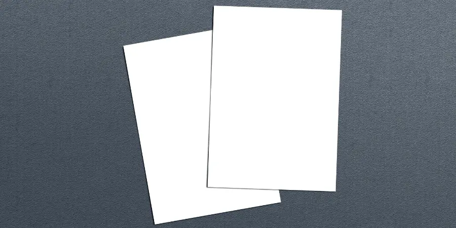 Two blank white letter size papers on dark textured background for office, printing, or document templates