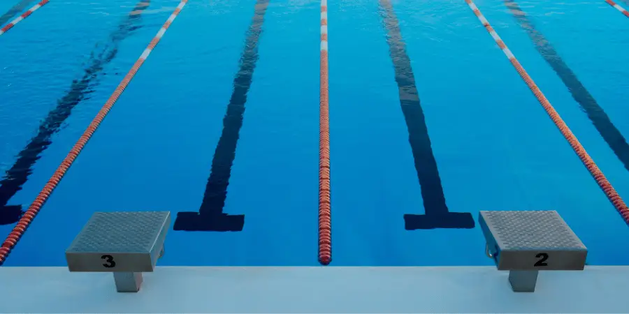 Olympic swimming pool with starting blocks, lane ropes and clear blue water prepared for competitive swimming events now