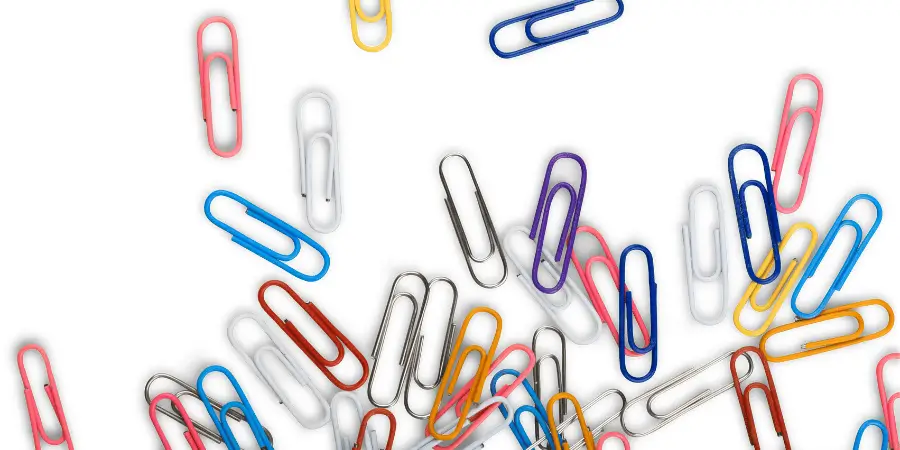 Colorful paper clips scattered on a white background, representing everyday office supplies.