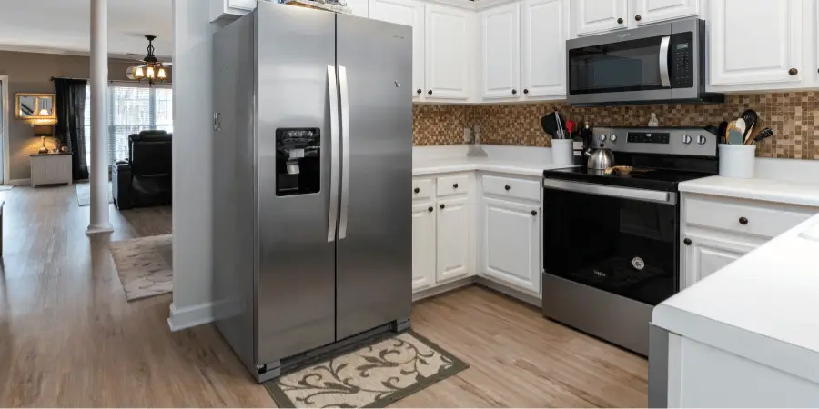 Modern kitchen featuring stainless steel appliances, white cabinetry, and hardwood flooring.