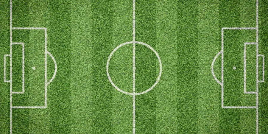Aerial view of open soccer field with center circle, penalty areas and striped green turf ready for matches and training