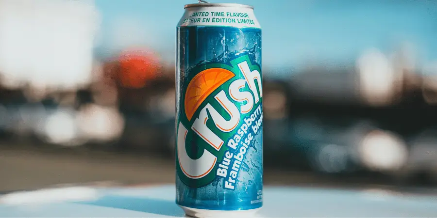 Crush blue raspberry soda can with vibrant branding on outdoor background for refreshing beverage concept