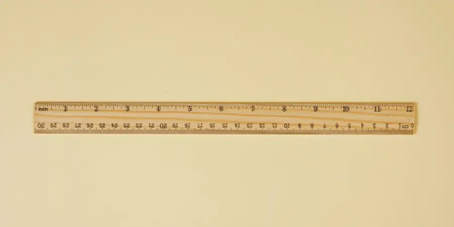A wooden ruler with measurements in inches and centimeters placed on a beige background.
