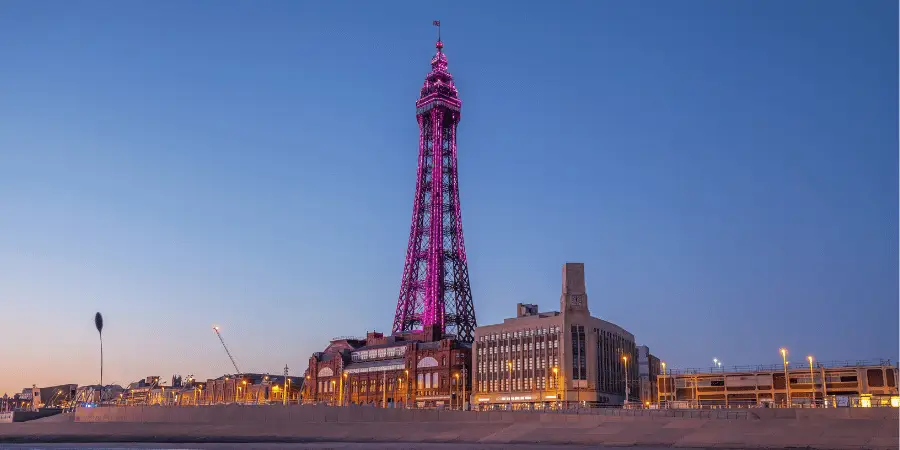 Blackpool Tower illuminated at sunset, iconic seaside landmark in England, famous tourist attraction with glowing pink lights.