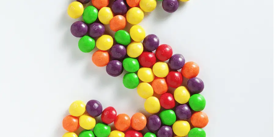 A collection of colorful Skittles candies arranged in a curving pattern.